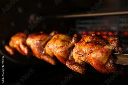 Fototapete Grilling whole chickens in rotisserie machine, closeup