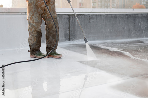 A person using high-pressure equipment to clean the bottom of a water pool. Cleaning dirt. Before and after situation. Uniform and rubber boots.