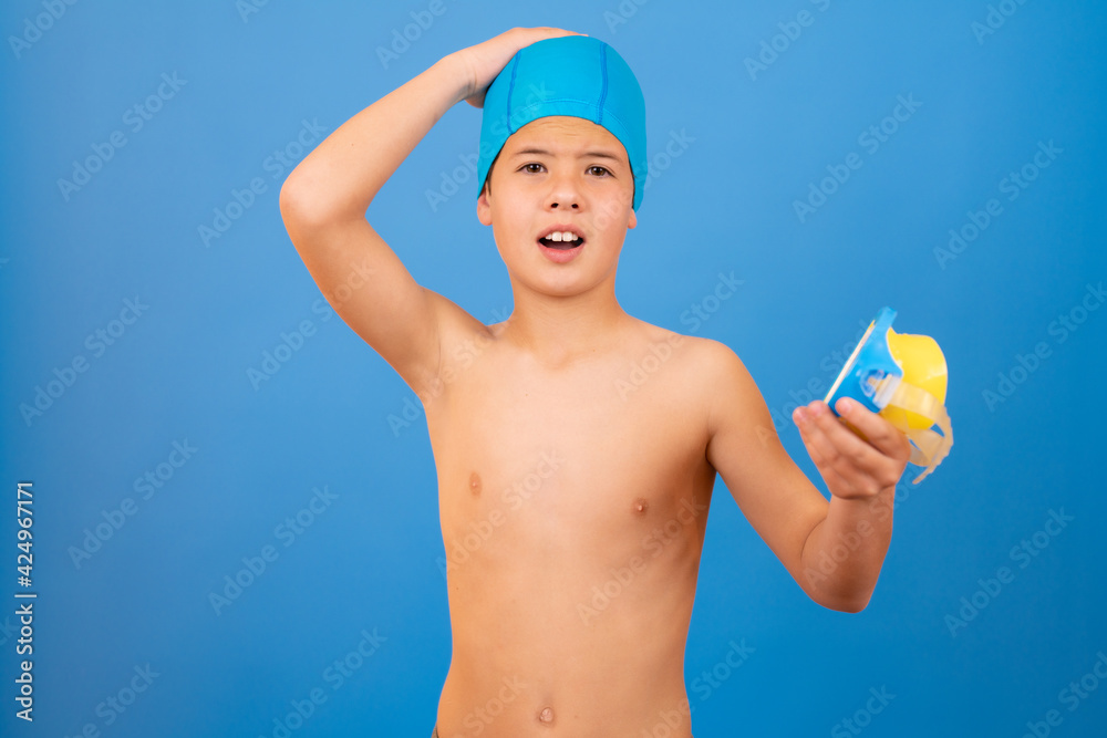Young boy with swimmer cap and diving goggles over blue background