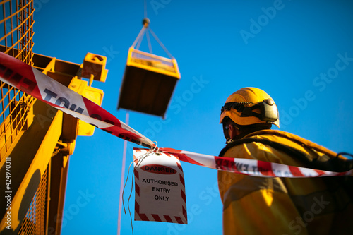 Safety work practice red and white warning danger tag tape sign applying on at working area exclusion dropped zone dropped object during rigger operating lifting heavy load in crane lifting cage  