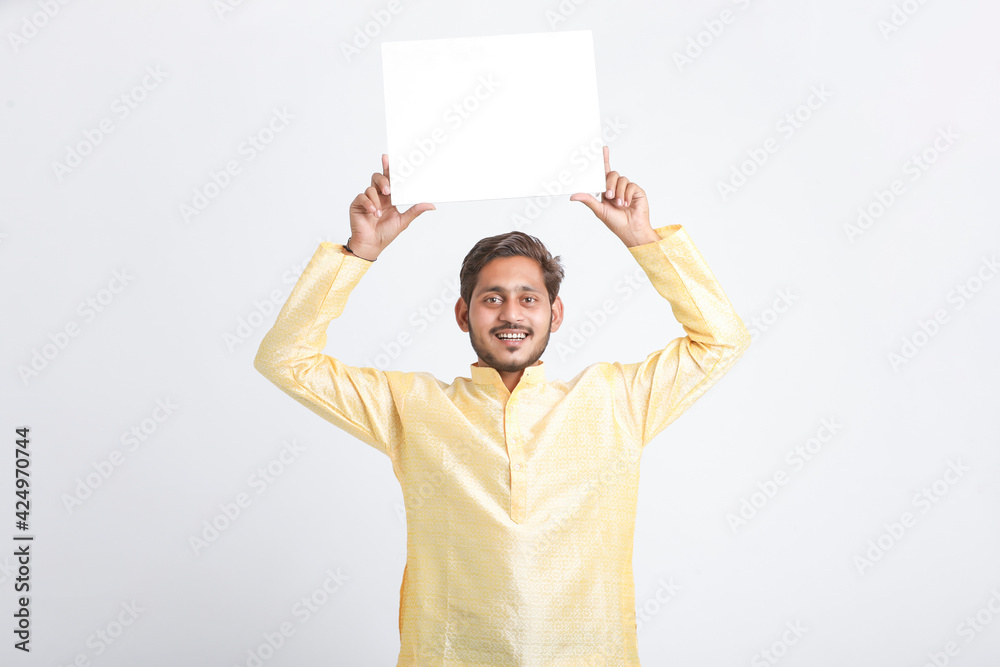 Indian man holding white board, promoting offers on festival season while wearing traditional cloths, standing over white background. Indian man holding white board, promoting offers on festival season while wearing traditional cloths, standing over white background.