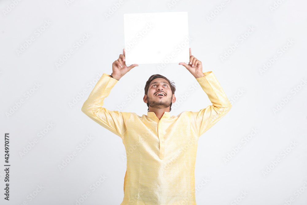 Indian man holding white board, promoting offers on festival season while wearing traditional cloths, standing over white background. Indian man holding white board, promoting offers on festival season while wearing traditional cloths, standing over white background.