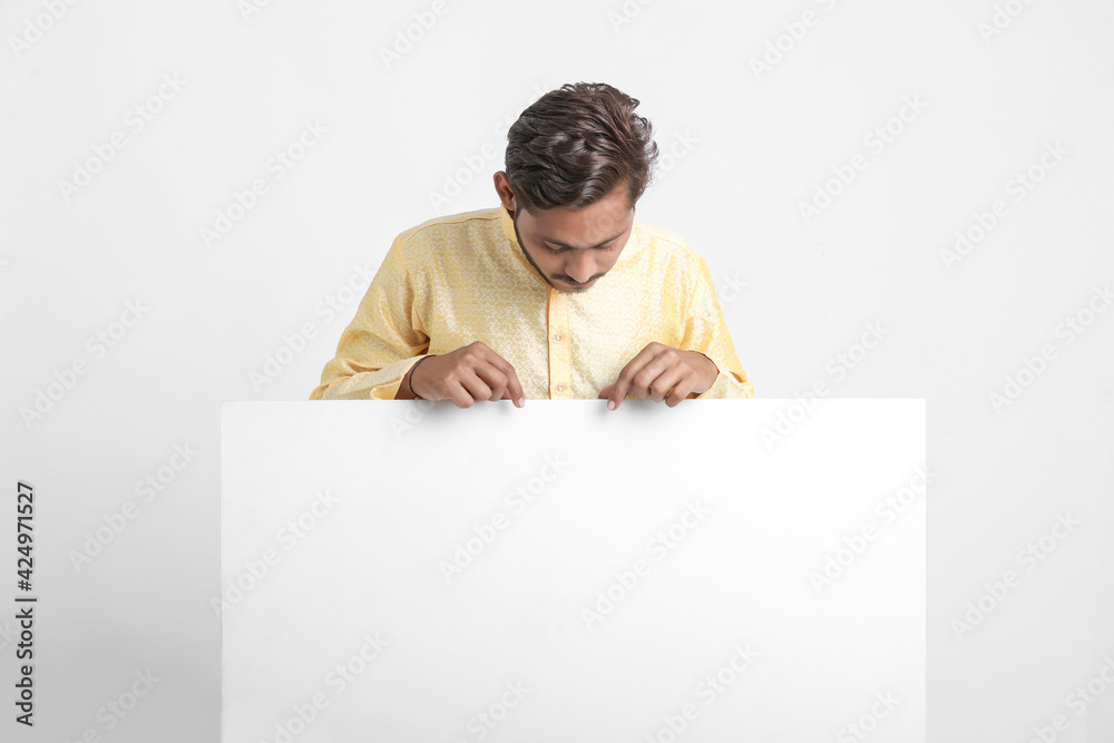 Indian man holding white board, promoting offers on festival season while wearing traditional cloths, standing over white background. Indian man holding white board, promoting offers on festival season while wearing traditional cloths, standing over white background.