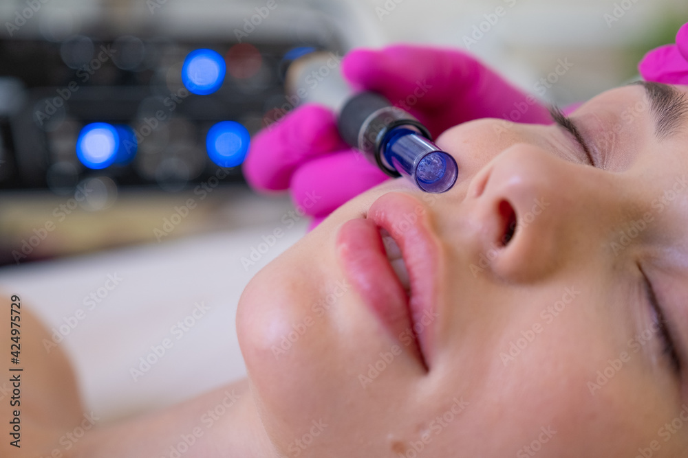 Woman in a spa salon on cosmetic procedures for facial care. Beautician makes skin care procedure on a face. Cosmetologist making a woman a therapeutic laser processing on a face.. Woman in a spa salon on cosmetic procedures for facial care. Beautician makes skin care procedure on a face. Cosmetologist making a woman a therapeutic laser processing on a face..
