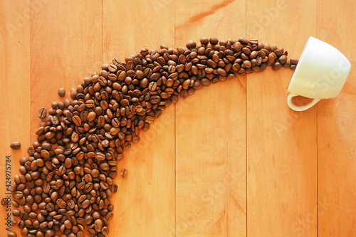 Coffee beans pouring from a coffee cup on the plane of the table top.