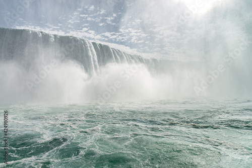 Horseshoe Falls, a part of Niagara Falls, with a sun shining through a tall dense cloud