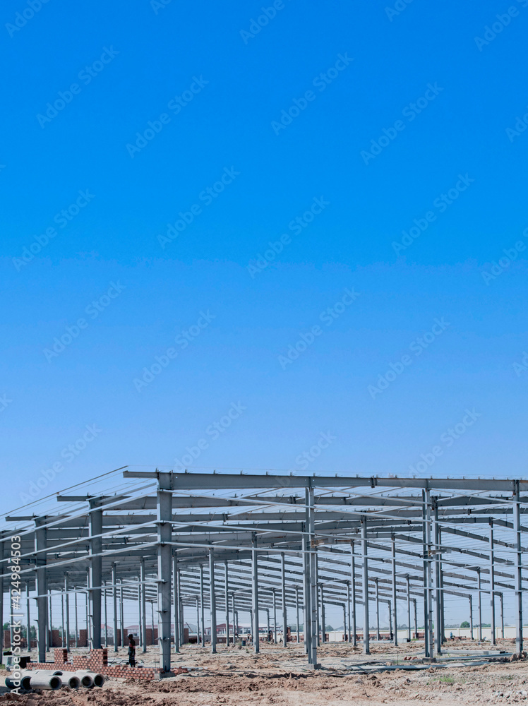 Large steel structure frame of a warehouse under construction. Factory and warehouse structure. Large steel structure frame of a warehouse under construction. Factory and warehouse structure.