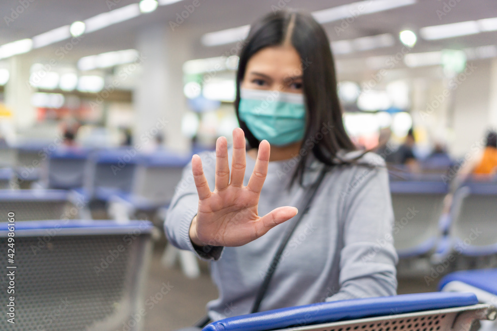 Asian woman wearing a surgical mask to protect against coronavirus, Lady sitting at Bangkok International Airport and show stop hands gesture. Asian woman wearing a surgical mask to protect against coronavirus, Lady sitting at Bangkok International Airport and show stop hands gesture.