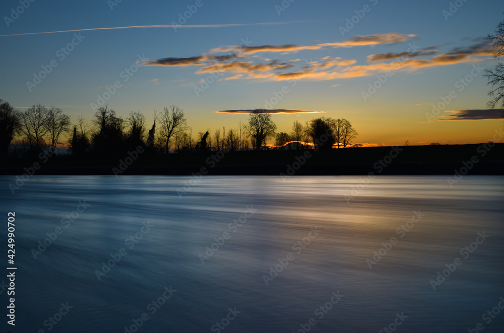 Fototapeta premium incredible sunset on the Muzza river, lights, colors and reflections surround this breathtaking landscape