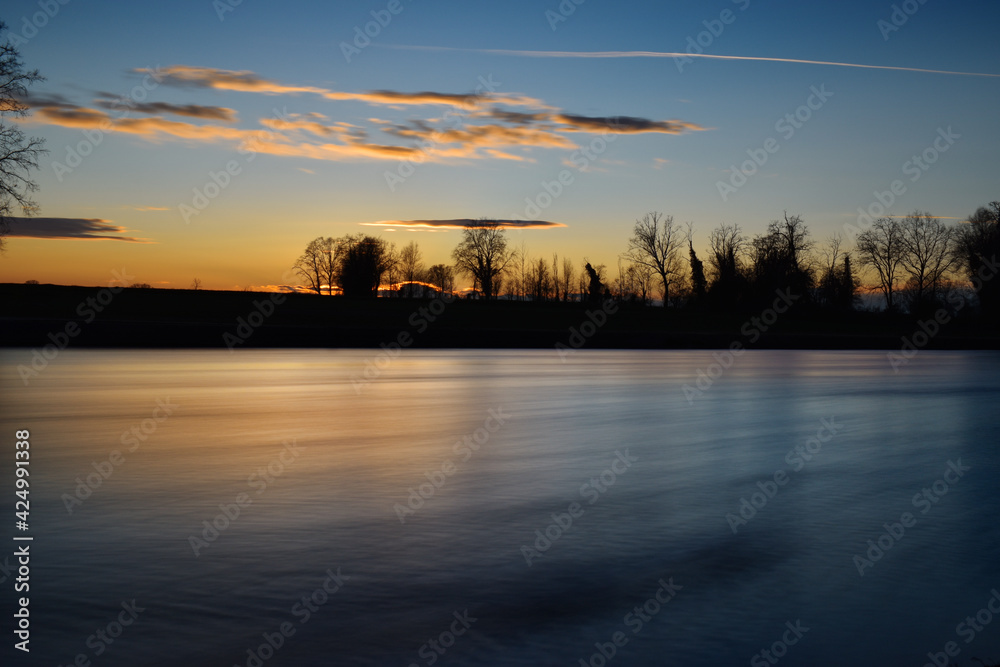 Fototapeta premium incredible sunset on the Muzza river, lights, colors and reflections surround this breathtaking landscape