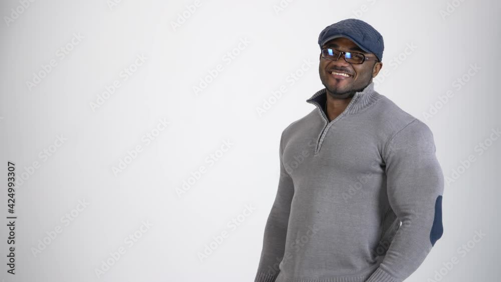 Portrait of a handsome african guy. Young stylish black man in gray sweater and cap wearing glasses standing in studio and smiling on camera. Copy space. Portrait of a handsome african guy. Young stylish black man in gray sweater and cap wearing glasses standing in studio and smiling on camera. Copy space.