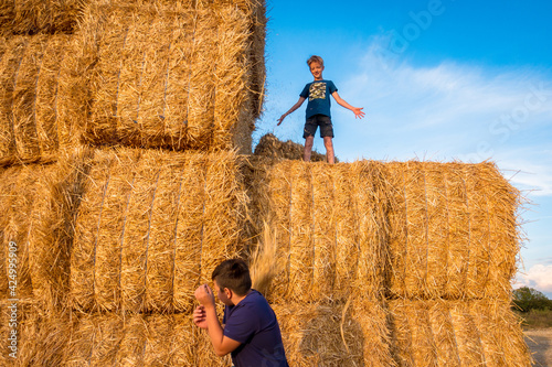Fotografie, Obraz Children play by a large haystack