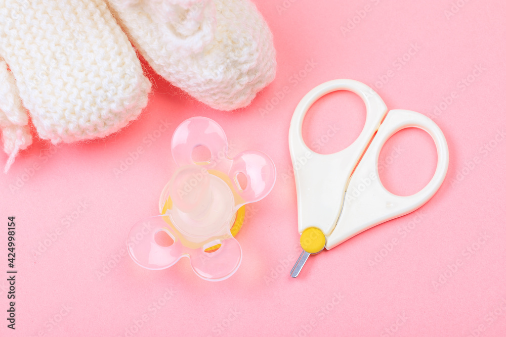 safe scissors, soother and booties for babies on pastel pink background . safe scissors, soother and booties for babies on pastel pink background .