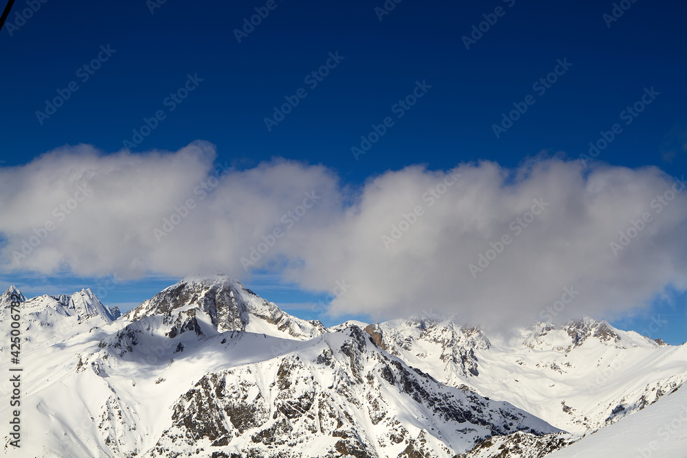 Beautiful snowy mountains, blue sky and clouds Dombay Karachay-Cherkessia.