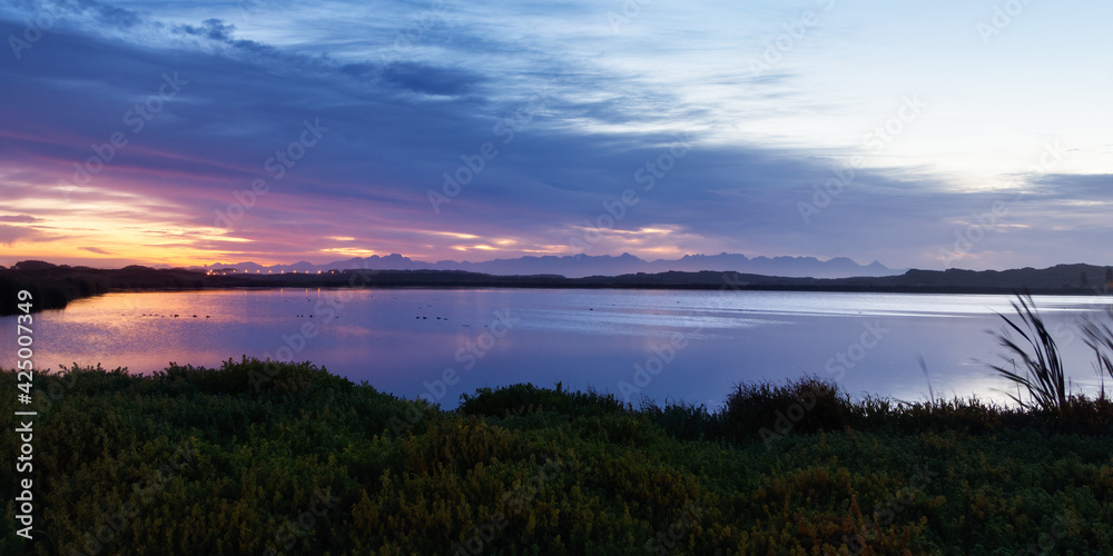 The sunrise is reflected in a lake in the False Bay Nature Reserve in Cape Town, South Africa.