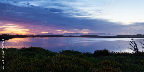 The sunrise is reflected in a lake in the False Bay Nature Reserve in Cape Town  South Africa.