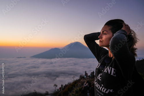 Young woman enjoying sunrise on top of the volcano