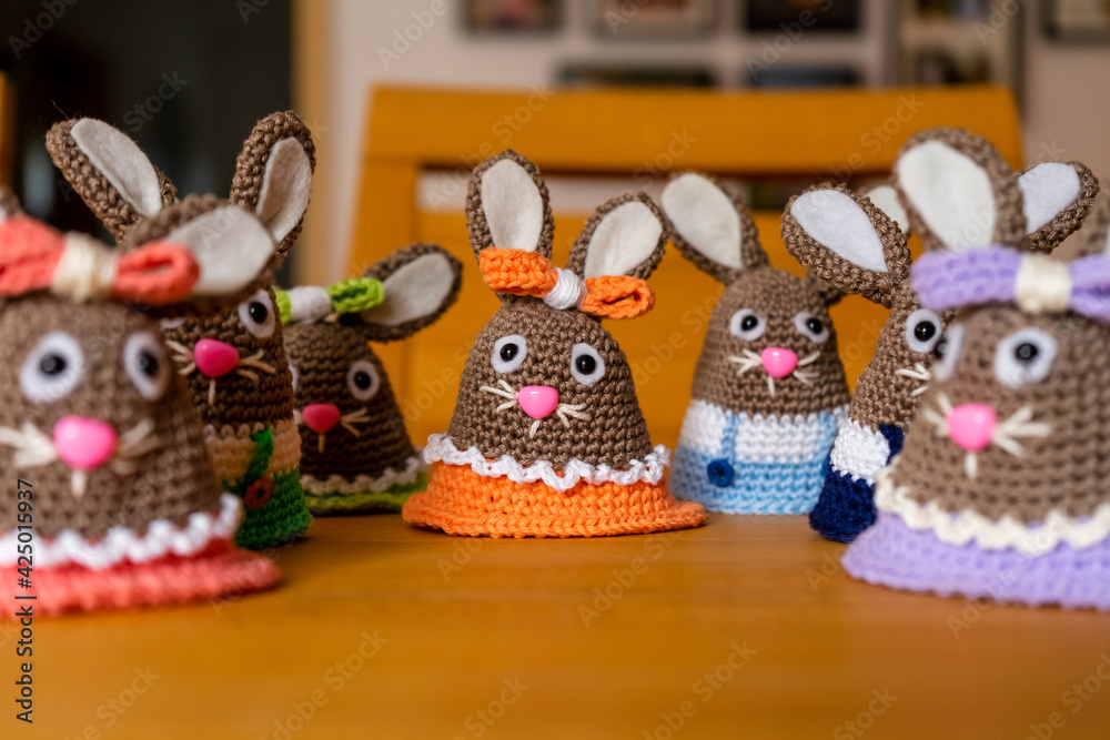 Homemade Amigurumi egg warmers crocheted from wool. In different scenes with a white and gray background and on a dining table.