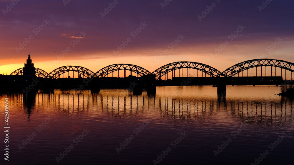 Dawn over the Daugava, the sun illuminates the railway bridge in Riga