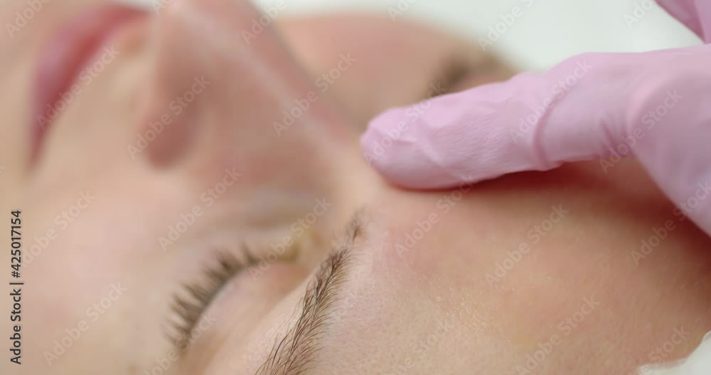 Portrait of young woman in cosmetology clinic. Cosmetologist is applying gel with hyaluronic acid on woman face, closeup view. Beautician doctor is making beauty procedure. Portrait of young woman in cosmetology clinic. Cosmetologist is applying gel with hyaluronic acid on woman face, closeup view. Beautician doctor is making beauty procedure.