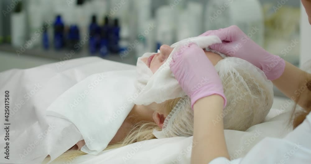 The beautician cleans the skin with a napkin after the cosmetic procedure. Beauty clinic concept.