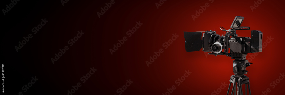 Digital film camera on dark red background, movie production or