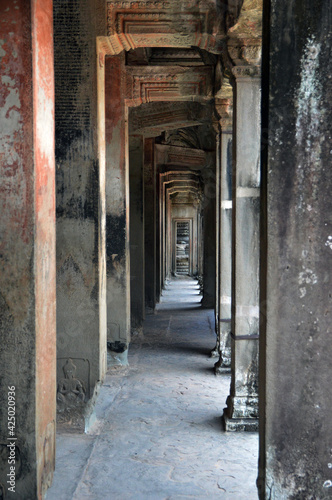 Empty corridor inside Angkor Wat complex with crafted Buddha on columns © hippomyta