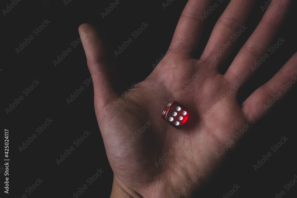 Red dice in hand on the black background. Roll the dice, six diced in hand. Game and gambling concept Red dice in hand on the black background. Roll the dice, six diced in hand. Game and gambling concept