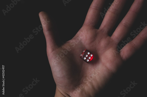 Red dice in hand on the black background. Roll the dice, six diced in hand. Game and gambling concept