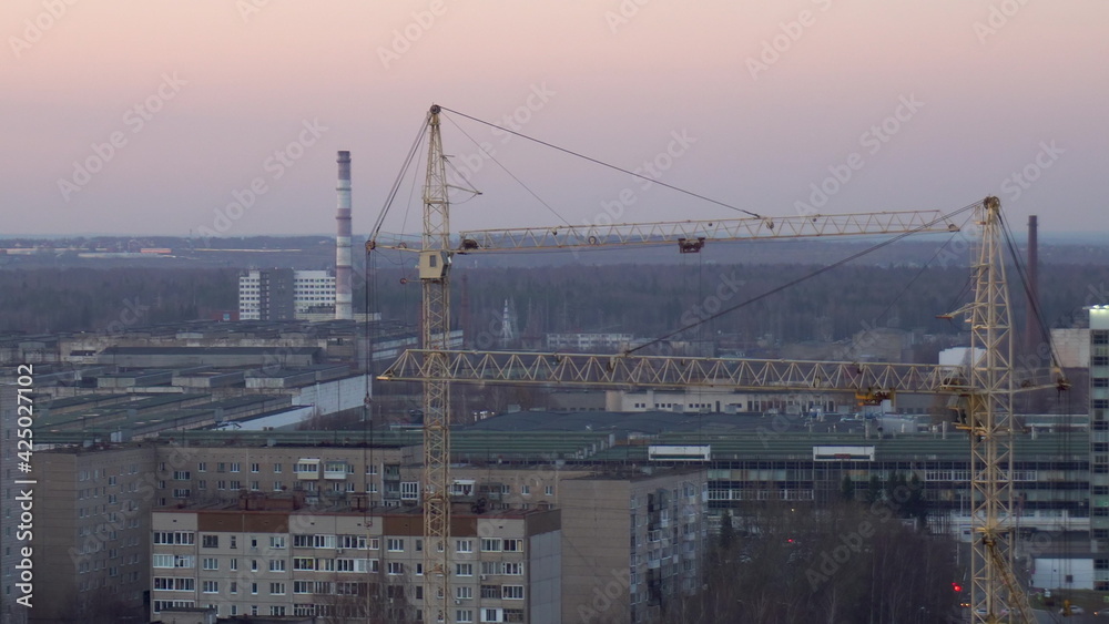 Two construction cranes are working at a construction site close-up.