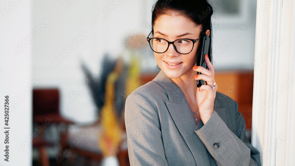 The concept of a business woman with glasses. A smart lawyer is in an office workplace in a coworking space. Talks to colleagues on the phone. Manager and favorite job.