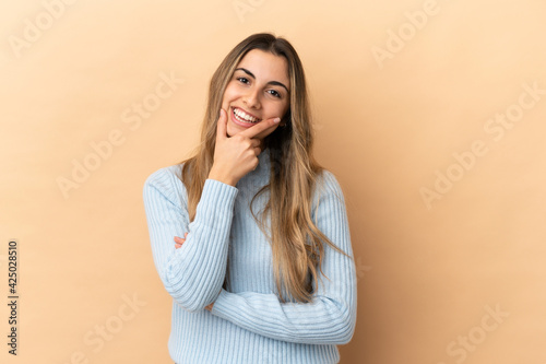 Young caucasian woman isolated on beige background happy and smiling