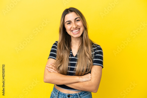Young caucasian woman isolated on yellow background keeping the arms crossed in frontal position