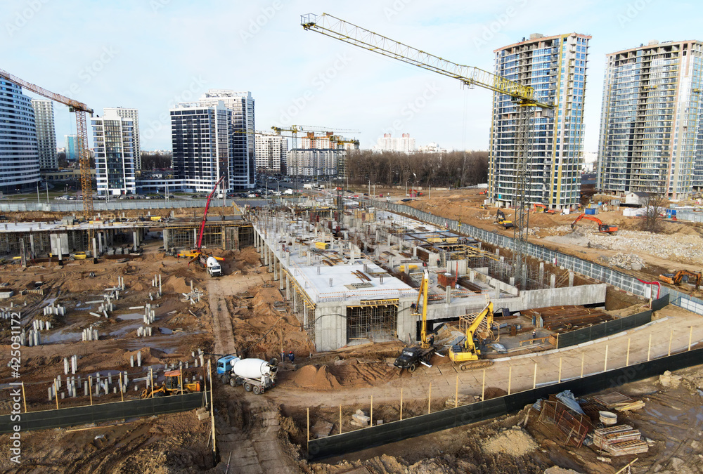 Drone view of a large construction site. Tower cranes in action. Housing renovation concept. Crane during formworks. Construction the buildings and multi-storey residential homes. Out of focus