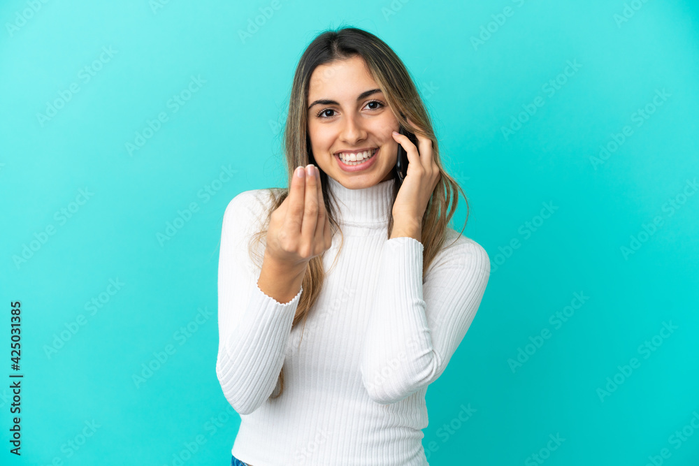 Young caucasian woman using mobile phone isolated on blue background making money gesture Young caucasian woman using mobile phone isolated on blue background making money gesture