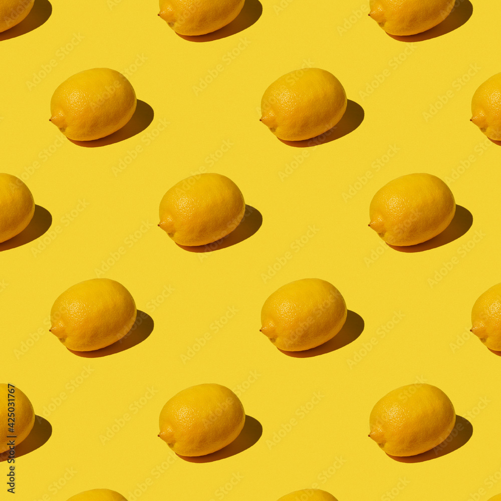 Seamless Pattern of a fresh whole yellow lemon on a yellow background with a hard shadow. Lemon pattern. Summer, fruits, vitamins concept.
