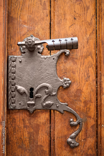 Large iron antique lock with handle and keyhole on a wooden old door from planks.