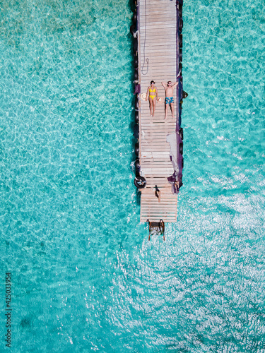 Playa Kalki Curacao tropical Island in the Caribbean sea, Playa Kalki western side of Curacao Caribbean Dutch Antilles azure ocean, drone aerial view of couple men and woman on the beach from above photo