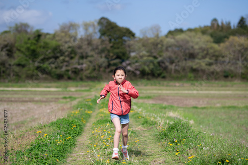 春のあぜ道で走る子供