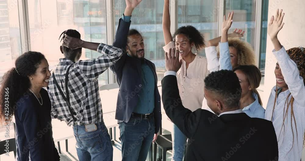 Seven diverse employees putting hands together in center of circle, then raise and cheering, make one for all gesture of unity and teamwork, synergy and loyalty. Team building meeting activity concept