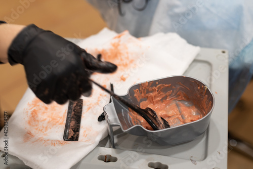 Hand with glove leaving dyeing brush close up