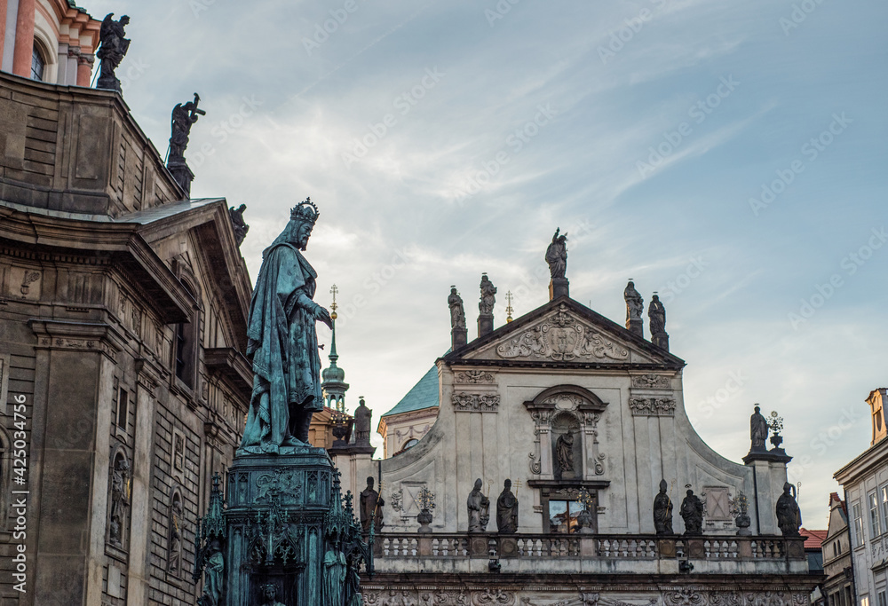 Carlo Cuarto monument to Charles IV in the background Church of St. Salvator. Prague at sunset. Antique small church with statues on the roof against the backdrop of the sunset sky.