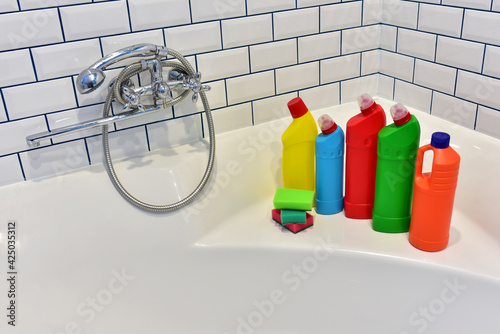 Detergent and sponge in bathroom on background of white tiles. Detergents bottles and kitchen sponges. Household chemicals cleaning of the restroom. Anti-bacterial liquids for ​house clean and toilet