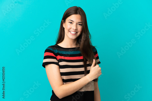 Teenager Brazilian girl over isolated blue background giving a thumbs up gesture