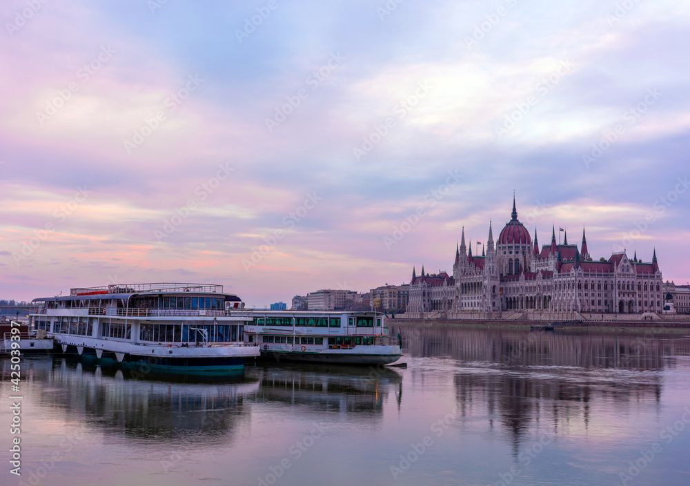 Morning in Budapest, parliament against the backdrop of a dramatic sky, ships on the river, reflected in the water