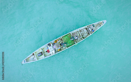 Fishing boat in blue sea water, fishermen set nets for fish. Aerial top view