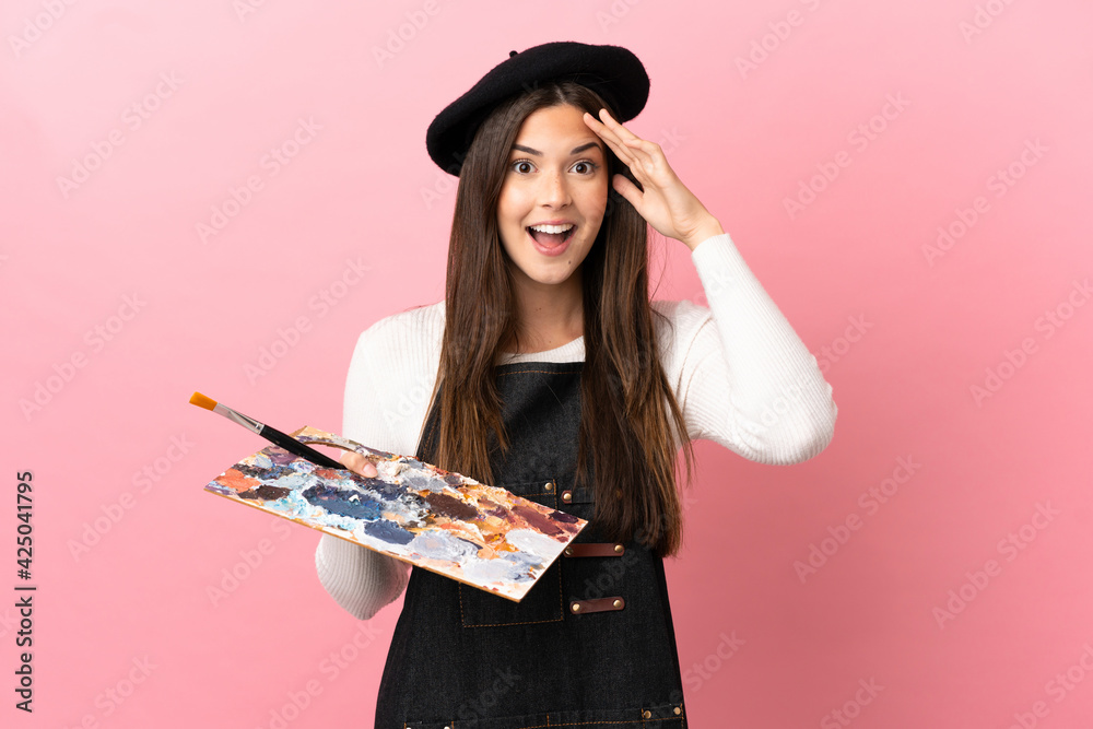 Φωτογραφία Young artist girl holding a palette over isolated pink background with surprise
