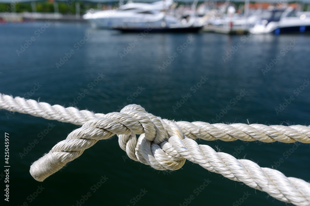 Yachting and marine concept. Close-up of a sea knot on a blurred background of boats moored in the harbor Yachting and marine concept. Close-up of a sea knot on a blurred background of boats moored in the harbor