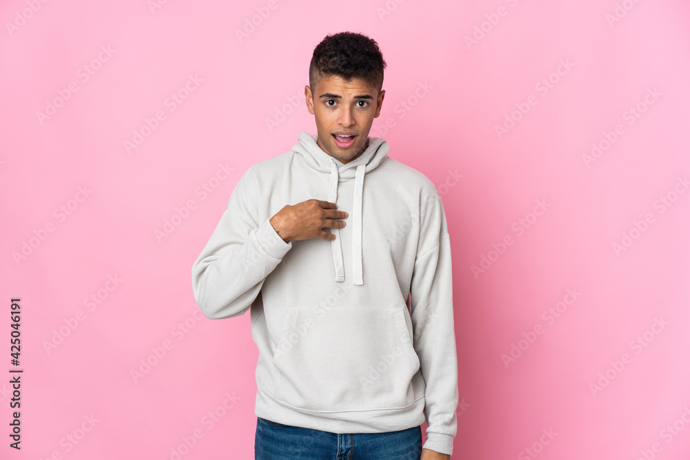 Young Brazilian man isolated on pink background pointing to oneself