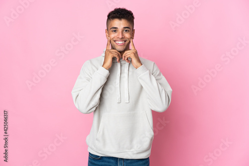 Young Brazilian man isolated on pink background smiling with a happy and pleasant expression © luismolinero